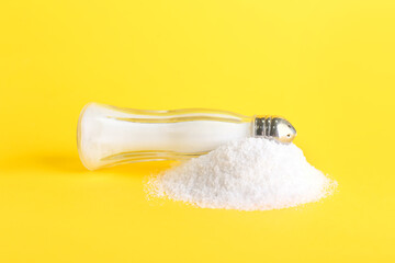 Saltcellar and heap of salt on color background
