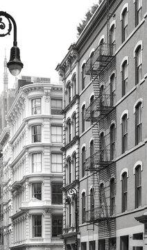 Old building with iron fire escapes, black and white picture of New York cityscape, USA.