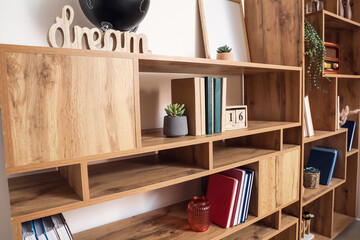 Fototapeta na wymiar Modern shelf unit with books and decor near light wall