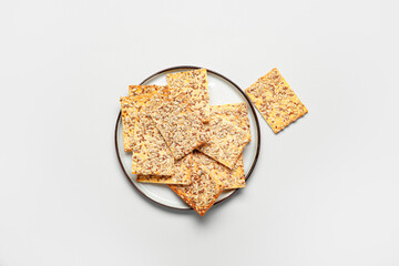Tasty crackers with seeds in plate on white background