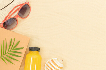 Summer background - sandy beach with accessories for leisure - hat, sungrasses, book, juice