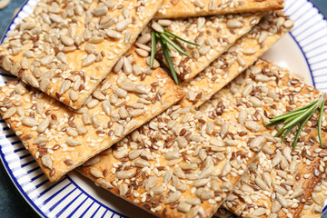 Tasty crackers with seeds in plate, closeup