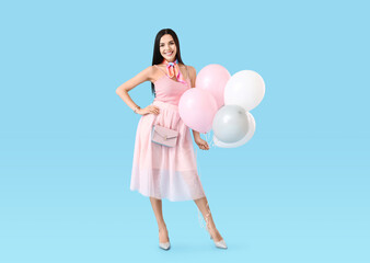 Beautiful young woman with balloons on color background