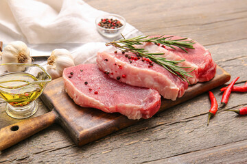 Board with fresh raw meat and spices on wooden background