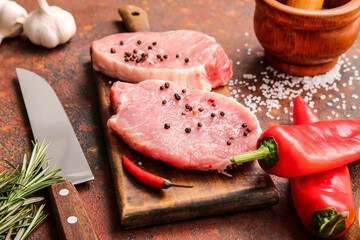 Board with fresh raw meat and spices on grunge background