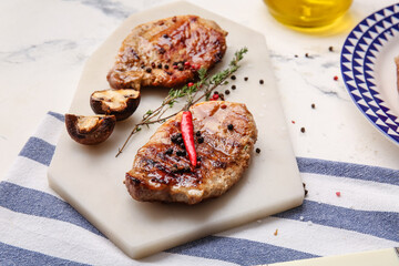 Board with tasty steaks and spices on table