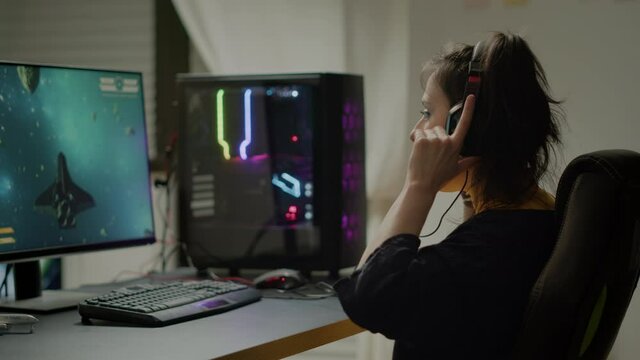 Pro woman video game r using headset and powerful computer playing online space shooter video games in gaming room. Virtual streaming cyber wearing headphones performing online tournament