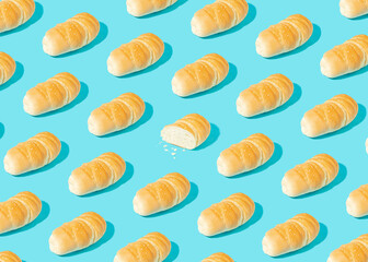 Real life bakery pattern made of fresh homemade cryspy bread on pastel blue background. Sliced pastry. Bright light, sharp shadows.