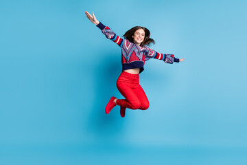 Fototapeta na wymiar Full length body size view of pretty cheerful girl jumping like airplane having fun isolated over bright blue color background