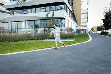 Businessman running in front of office buildings.