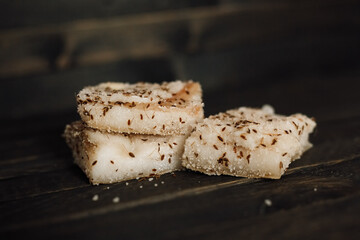 Pieces of homemade salted lard with dill on a wooden background.