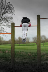 gymnast training on the bars in the park