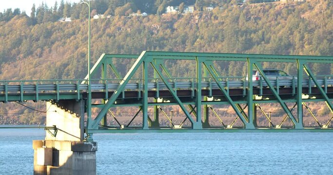 Cars drive through Hood River Bridge steel truss construction on Columbia River