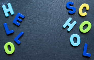 Lettering Hello school. Frame from multicolored letters on black stone background. Topview. Copyspace. Concept back to school.