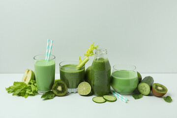 Glasses of green smoothie and ingredients on white table