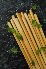 Grissini breadsticks with salt and basil on black smoky background