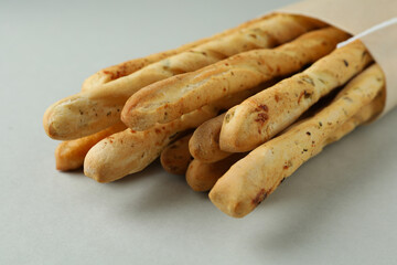 Craft paper with grissini breadsticks on light gray background