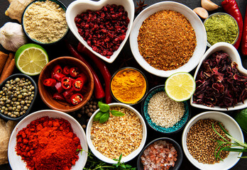 Various spices in a bowls on black concrete background. Top view copy space.