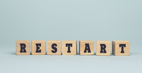 The word Restart made from wooden cubes on blue background