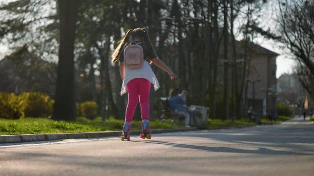 Little girl with a backpack  travels to school on roller skates. Slow motion. Back to school 