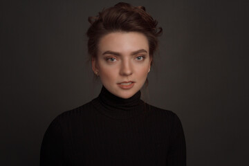 Young brunette woman, with gathered hair hairstyles, in the studio on a black background