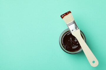 Glass jar of barbecue sauce and brush on mint background