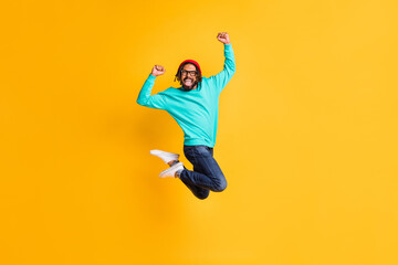 Fototapeta na wymiar Full size profile photo of brunette optimistic guy jump wear cap spectacles pullover jeans isolated on yellow color background