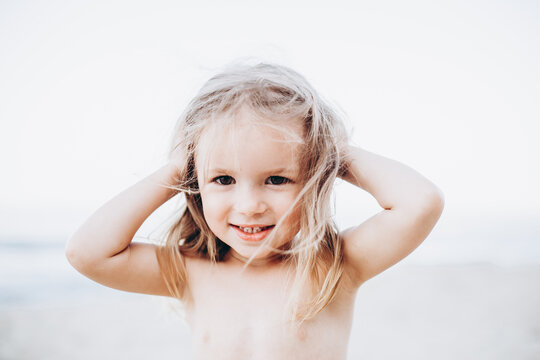 Portrait of a little 3-year-old girl posing for a photo by the sea during swimming, sunbathing and summer vacation