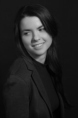 Black and white portrait of a young brunette woman in a studio on a black background