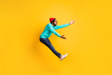 Fototapeta na wymiar Full size profile photo of brunette optimistic guy jump catch wear cap spectacles pullover jeans isolated on yellow background