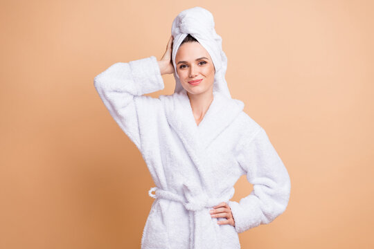Portrait of charming cheerful girl wearing white bathrobe enjoying relax isolated over beige pastel color background
