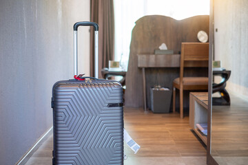 Grey Luggage in modern hotel room with windows, curtains and bed. Time to travel, relaxation, journey, trip and vacation concepts