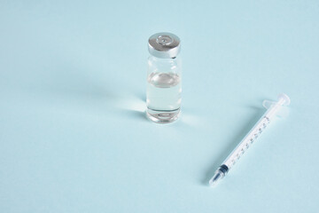 insulin syringe and injection medicine vial on blue background copy space