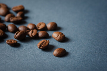 Coffee grain blue background top view. Textured background for the design. Brown roasted macro beans scattered on the table in natural sunlight. Full frame, copy space. Espresso beans, mock-up