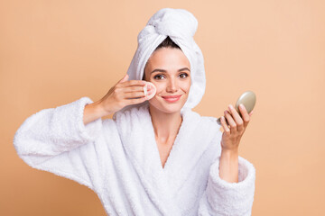 Portrait of pretty cheerful girl wear bathrobe applying blush powder tone correction isolated over beige pastel color background