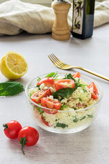 Fresh home-made tabouli, or tabbouleh salad, with its ingredients, side view on grey background