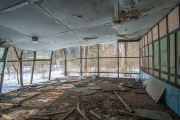 Abandoned old dining room in a camp in the woods with a roof that collapsed during the winter day.