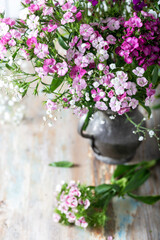 Fresh sweet william flowers in tones of pink on a wooden table in a vase.