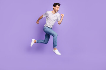 Fototapeta na wymiar Profile photo of guy jump run look empty space wear black t-shirt jeans footwear isolated violet background