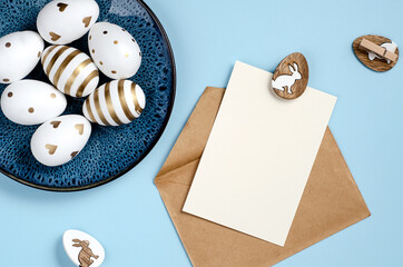 Happy Easter greeting card mockup with white and golden eggs on blue background. Top view photo