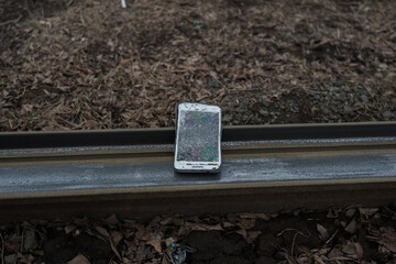 A crashed smartphone lies on the rail.
