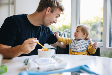Man on paternity leave feeding his baby - obrazy, fototapety, plakaty