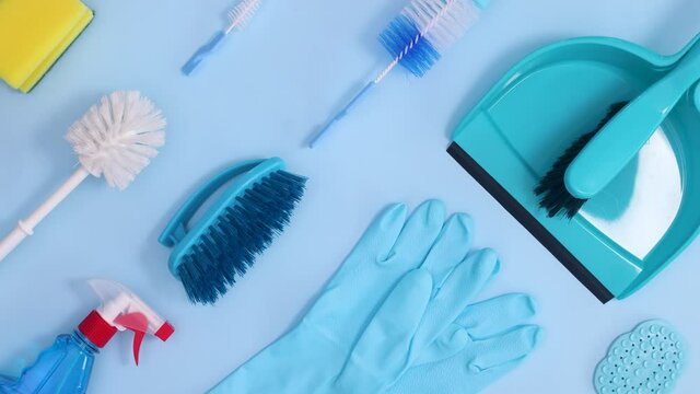 Household cleaning tools and supplies make creative pattern on bright blue background. Stop motion flat lay