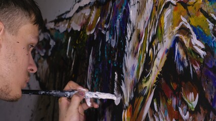 Artist designer draws an eagle on the wall. Craftsman decorator paints picture with acrylic oil color. Painter painter dressed in paint coat. Indoor.