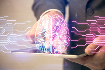 Double exposure of man's hand holding and using a digital device and brain hologram drawing. Data...