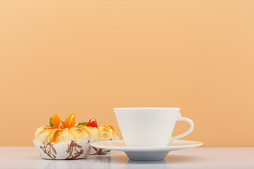 White ceramic tea or coffee cup with pastry next to it against beige background with copy space