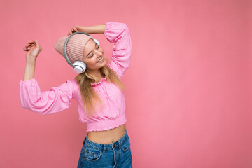 Beautiful happy smiling young blonde woman wearing pink blouse and pink hat isolated over pink...
