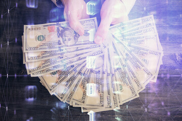 Multi exposure of technology drawing hologram and us dollars bills and man hands. Data concept