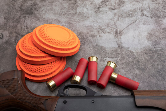 Clay disc flying targets and shotgun with bullet shells on texture background ,Clay Pigeon target game