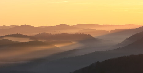 sun rays lighting a foggy valley during sunrise